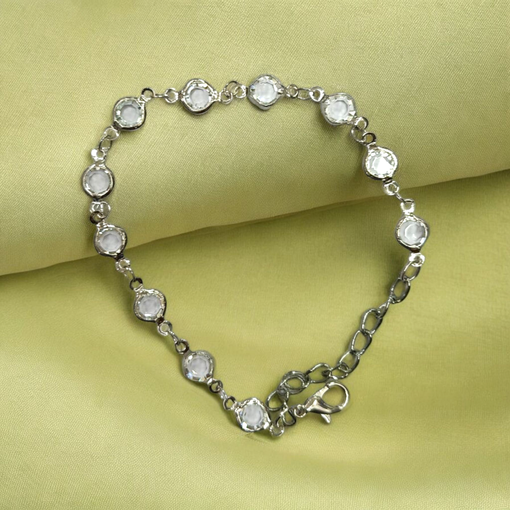 Silver bracelet with clear stones on a green fabric background